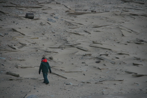 Dressed head to toe in insulated rain gear, a researcher walks among the debris field of the old East Lighthouse that has been destroyed by decades of wind and shifting sands. Photo by Rob Ronconi